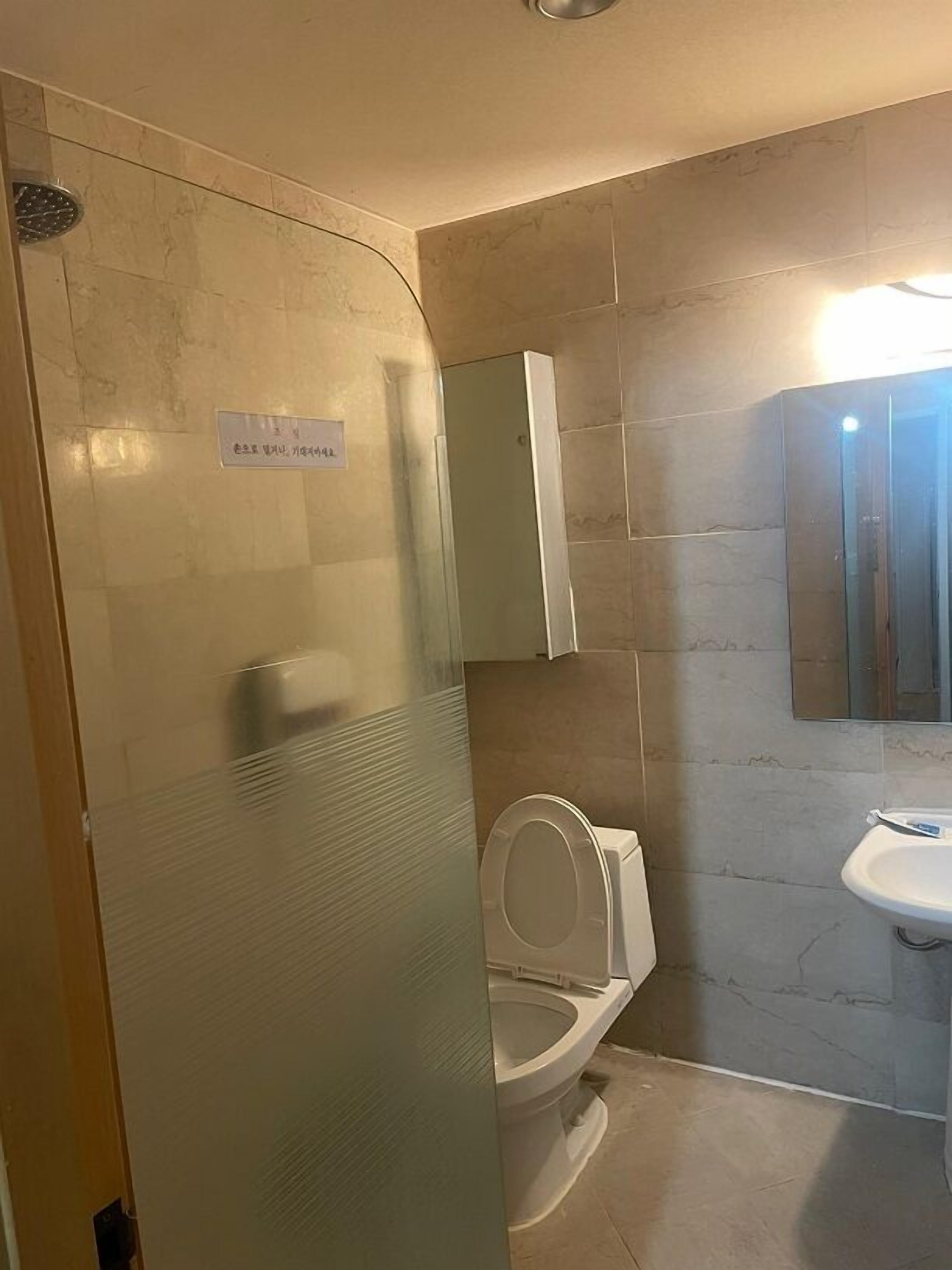 A bathroom with a glass-enclosed shower, a toilet, and a sink.