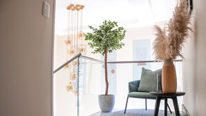 A modern interior with a staircase, a potted tree, a chair, and a vase with pampas grass. - 1945 On Kloof Guesthouse (Johannesburg)
