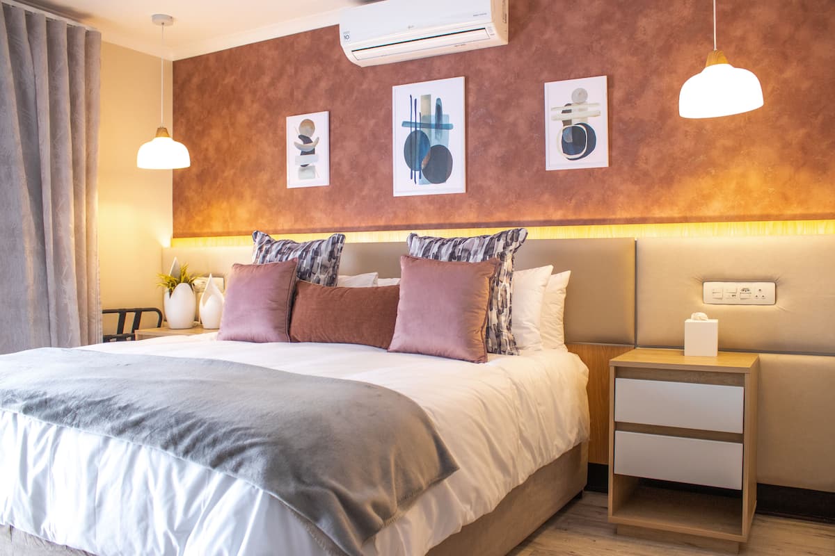 Une chambre d’hôtel moderne avec un grand lit, une table de chevet et un climatiseur fixé au mur.