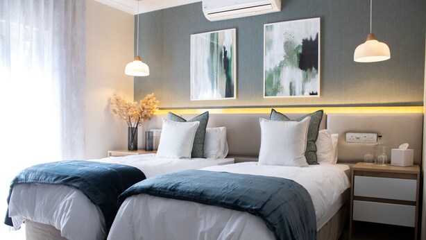 A modern hotel room with two beds, a nightstand, a bedside table, and artwork on the wall. - 1945 On Kloof Guesthouse (Johannesburg)