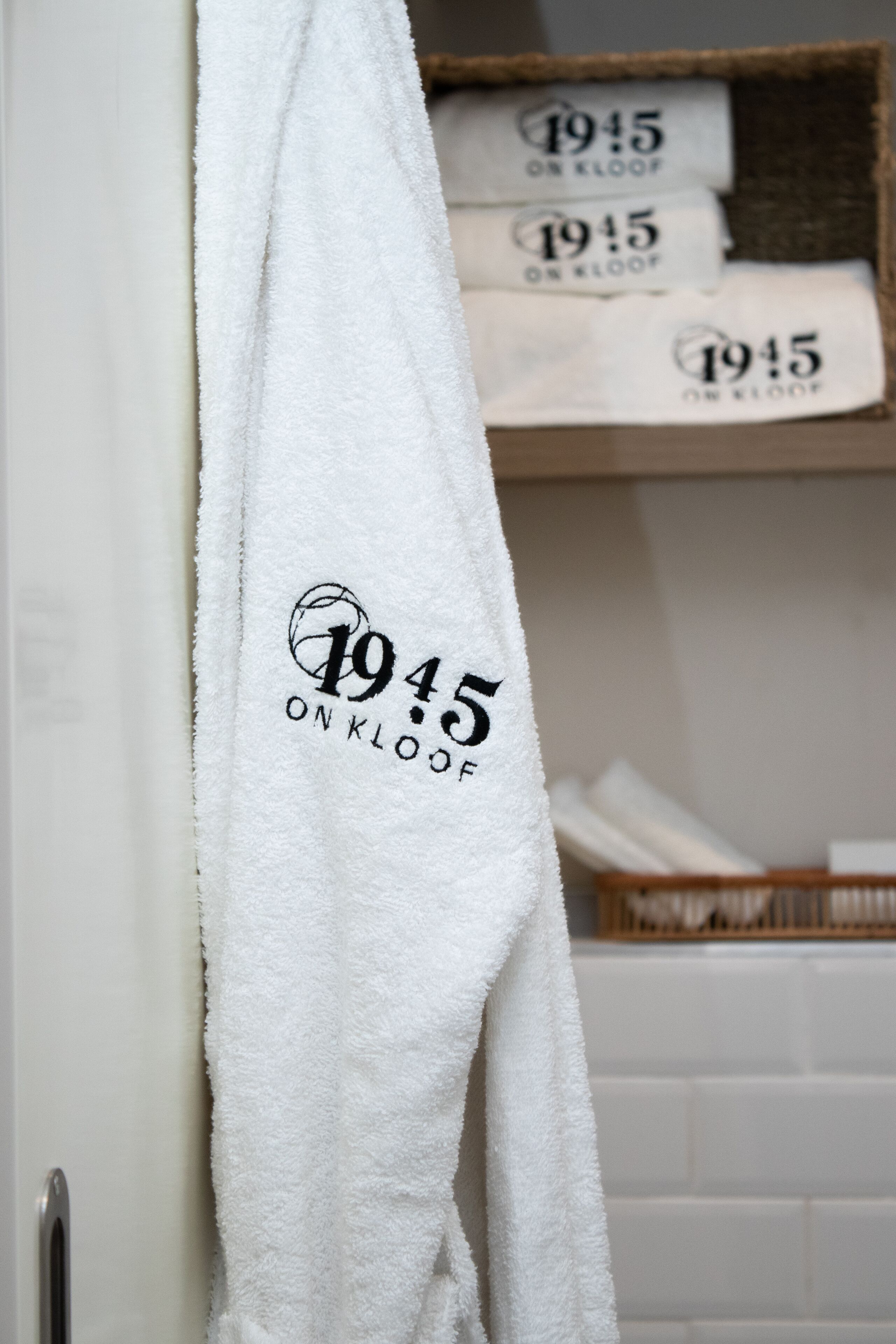 Una toalla blanca con la inscripción "1945 ON KLOOF" colgada de una puerta.