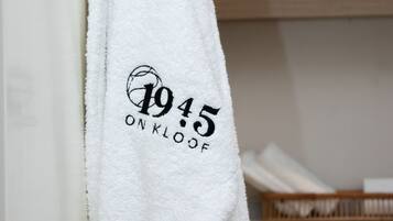 Una toalla blanca con la inscripción "1945 ON KLOOF" colgada de una puerta.