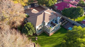 An aerial view of a house with a tiled roof, a balcony with outdoor furniture, and a swimming pool. - 1945 On Kloof Guesthouse (Johannesburg)