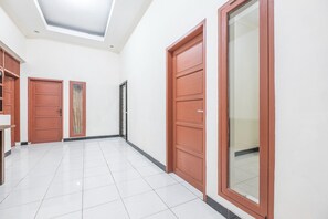 Un corridoio con pavimento in piastrelle bianche, porte in legno e un lucernario.