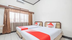 A hotel room with two beds, a window with curtains, a sink, and an air conditioning unit. - Hotel O Transit 1 (Makassar)