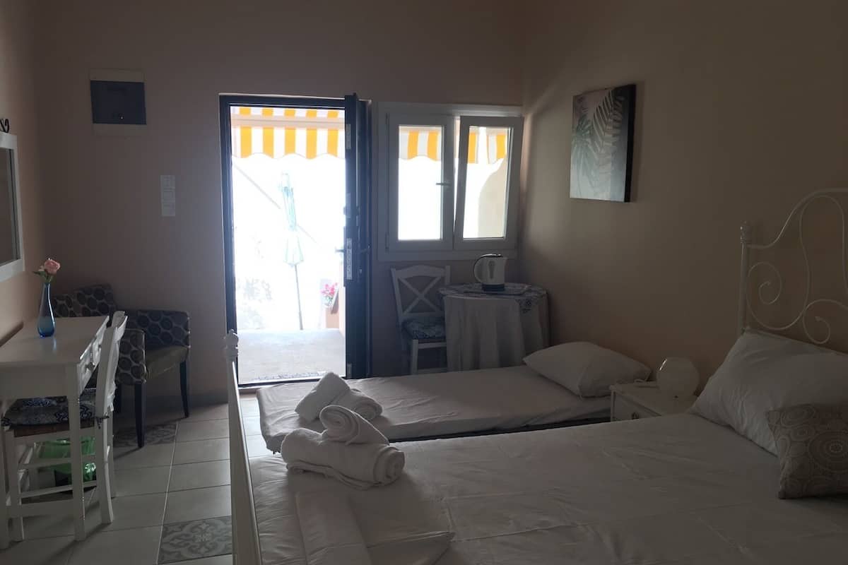 A hotel room with a bed, a desk with a chair, a small table with a chair, and a window with curtains.