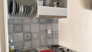 A compact kitchen with a sink, a stove, and a dish rack. -  Aphrodites Apartments (Syros)