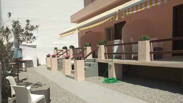 An outdoor seating area with concrete steps, a small table, and chairs. -  Aphrodites Apartments (Syros)