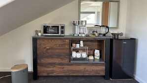 Eine Küchenzeile mit einer Mikrowelle, einer Kaffeemaschine und einem Kühlschrank.