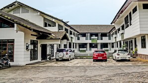 Un immeuble à plusieurs étages doté d’une cour intérieure, qui présente un mélange d’éléments architecturaux modernes et traditionnels, notamment un toit en tuiles et un grand espace ouvert au centre.
