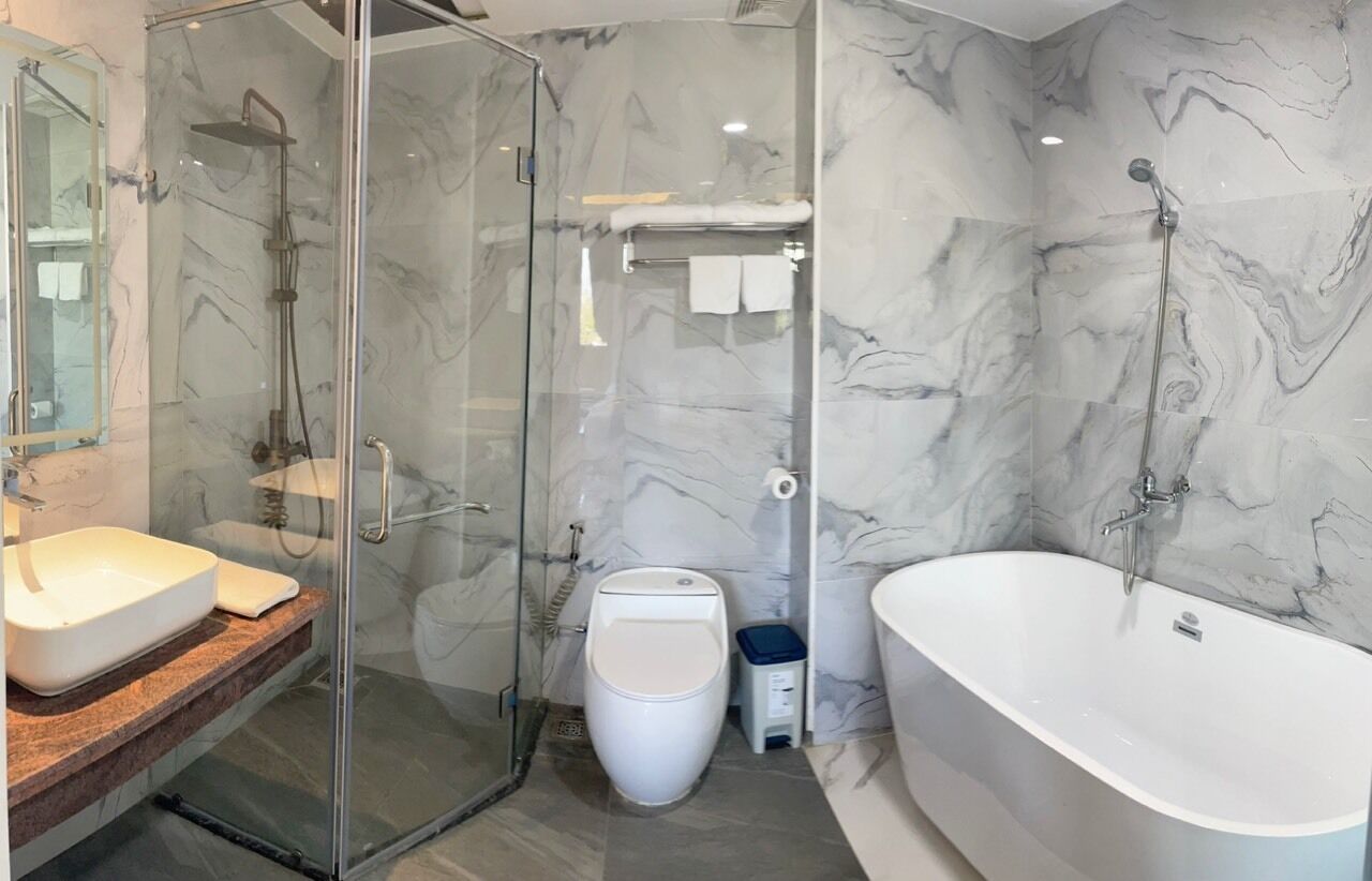 A modern bathroom with a glass-enclosed shower, a freestanding toilet, and a large bathtub.