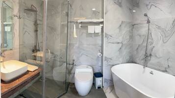 A modern bathroom with a glass-enclosed shower, a freestanding toilet, and a large bathtub.