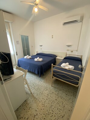 A hotel room with two beds, a desk, a chair, a ceiling fan, and an air conditioning unit. - B&B HOTEL LUCCIOLA (Cattolica)