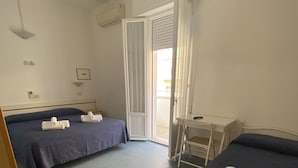 A hotel room with two beds, a desk, and a ceiling fan. - B&B HOTEL LUCCIOLA (Cattolica)