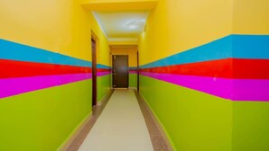A brightly colored hallway with a tiled floor and a door at the end. - MeroStay 113 Hotel TMT (Kathmandu)