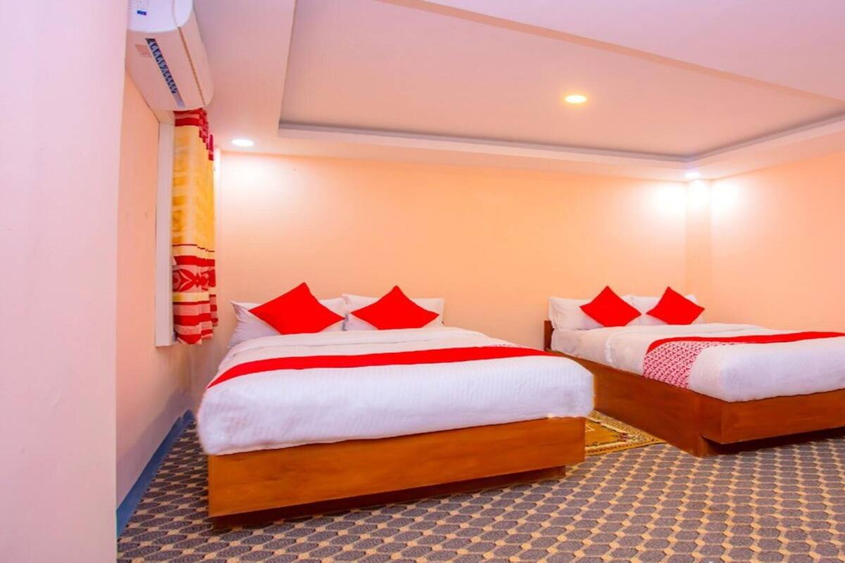 Una habitación de hotel con dos camas individuales, cada una con ropa de cama roja y blanca, y un suelo con diseño.