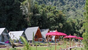 Un complexe hôtelier comprenant plusieurs chalets de style bungalow, des espaces de détente en plein air et un jardin luxuriant.