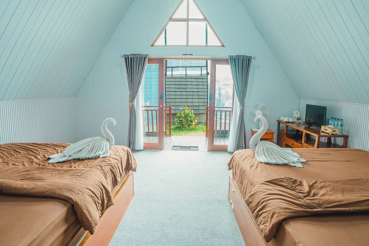 Ein Zimmer mit zwei Betten, einem Fernseher und Blick ins Freie.