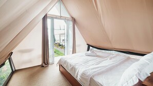 Une chambre avec une grande fenêtre, un lit et une vue sur l’extérieur.