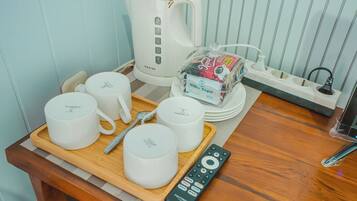 Una kitchenette con una cafetera, un paquete de azúcar blanca y varias tazas blancas sobre una bandeja.