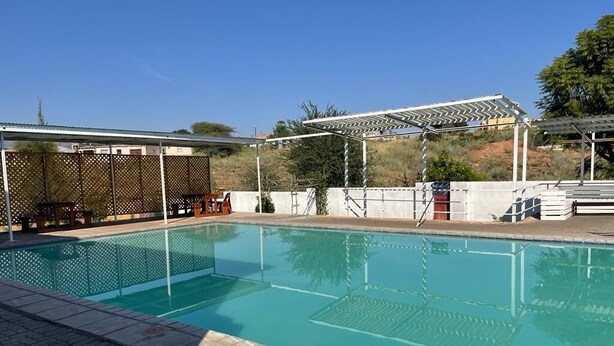 A swimming pool with a pergola and a covered seating area. - Shakwaneng Lodge (Greater Tubatse)