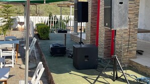 An outdoor patio area with a Heineken-branded umbrella, outdoor speakers, and a brick wall. - Shakwaneng Lodge (Greater Tubatse)