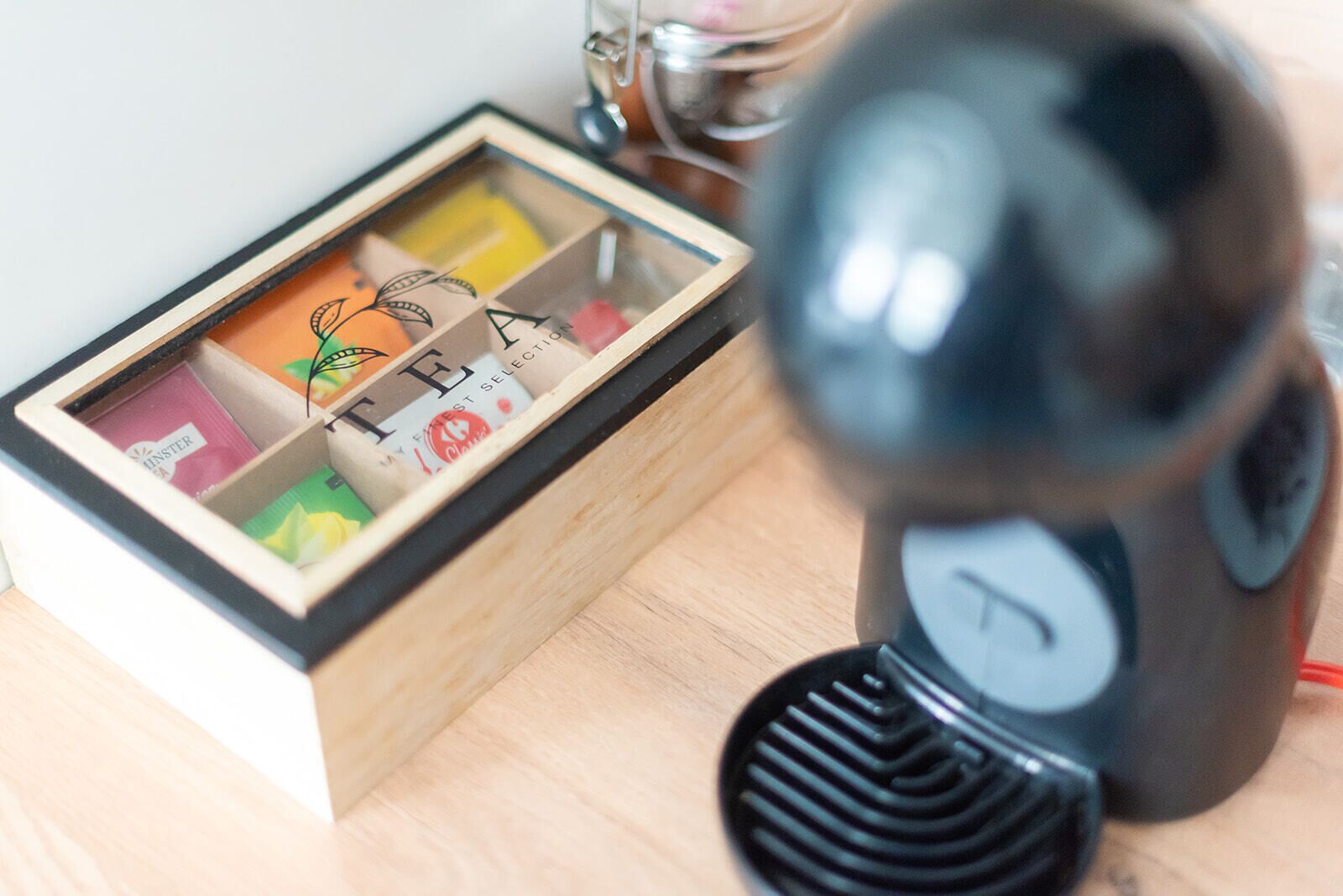 Une boîte en bois dotée de compartiments contenant divers objets, et un objet noir muni d’un cadran à l’avant.