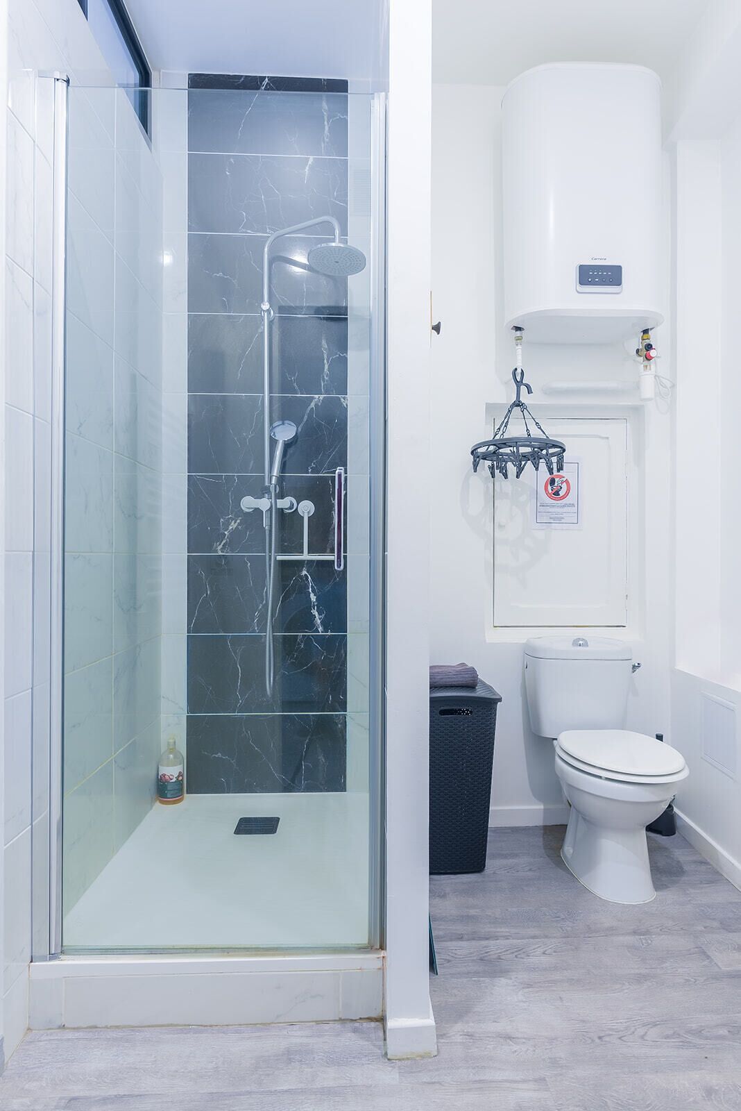 Ein Badezimmer mit einer gläsernen Duschkabine, einer Toilette und einem Mülleimer.
