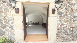 A stone archway leading to a dining area with tables and chairs.