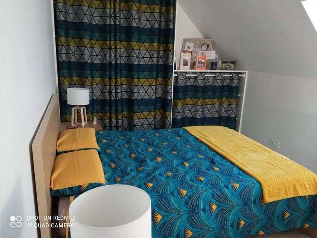Ein Schlafzimmer mit einem geblümten Bettbezug, einer Nachttischlampe und einem Stauraum mit gerahmten Fotos.