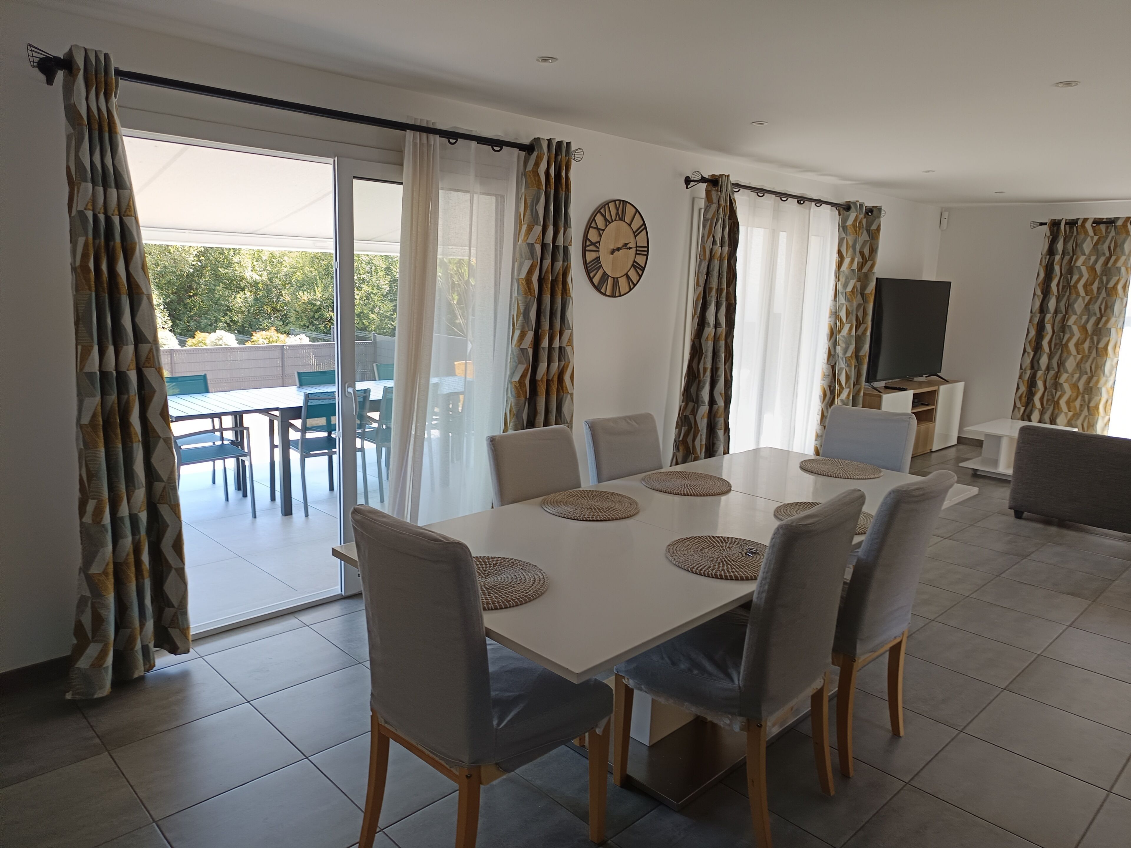 A dining area with a table, chairs, and a television.
