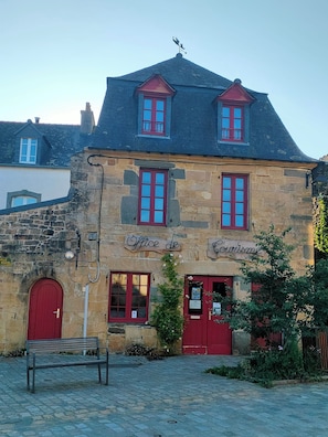A stone building with a red door and windows, labeled "Office de Courisme." - Maison Familiale (LE FAOU)