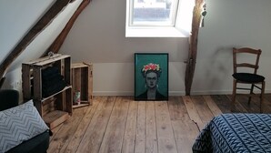 A loft bedroom with exposed wooden beams, a skylight, a framed artwork, and a wooden floor. - Maison Ancienne au Calme (Soulaire-et-Bourg, France)