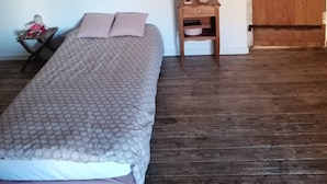 A bedroom with a bed, a nightstand, a teddy bear, and a wooden ceiling beam. - Maison Ancienne au Calme (Soulaire-et-Bourg, France)