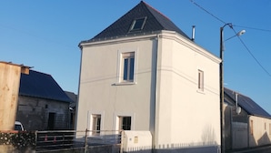 A two-story house with a sloped roof, a small window, and a garage attached to the side. - Maison Ancienne au Calme (Soulaire-et-Bourg, France)