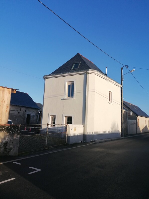 A two-story house with a sloped roof, a small window, and a garage attached to the side. - Maison Ancienne au Calme (Soulaire-et-Bourg, France)