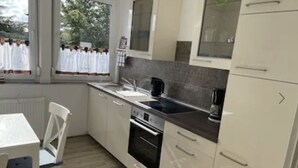 Una cocina moderna con gabinetes blancos, una estufa negra y una ventana con cortinas blancas.