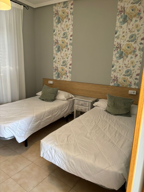 A hotel room with two beds, a nightstand, and a curtain. - Hostal el Bomba (Las Pedroneras)