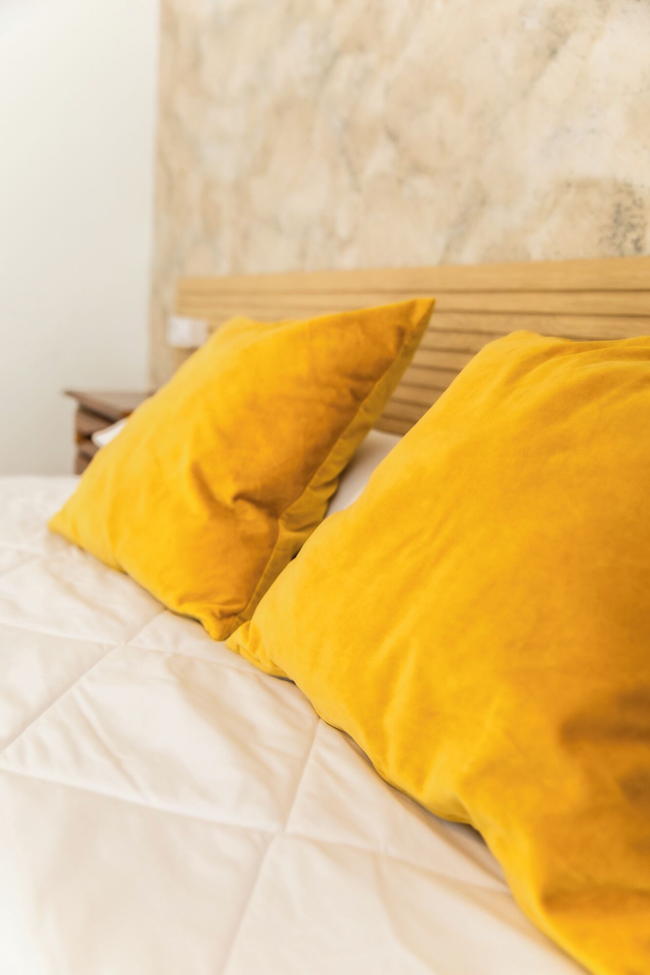 A bed with a white quilt and two yellow pillows.