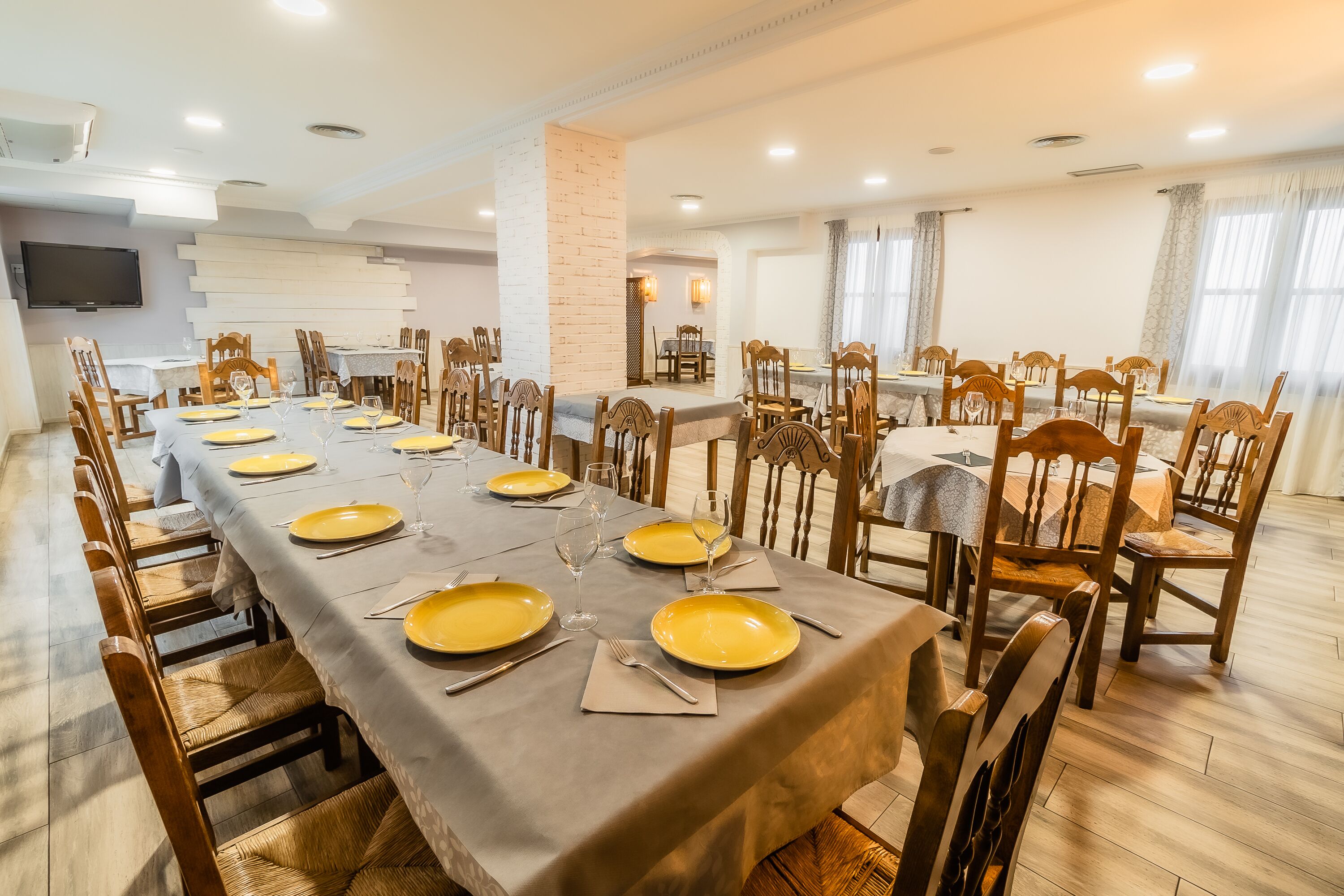 A dining area with a long table set for a meal, surrounded by wooden chairs.