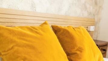 Una cama con ropa de cama blanca y dos almohadas color mostaza.