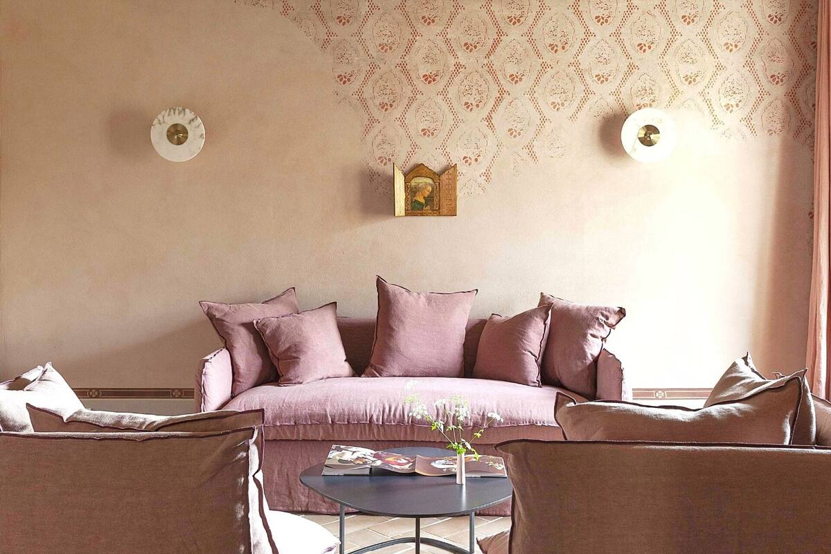 A cozy living room with a sofa, two armchairs, a small round table, and a decorative wall piece.
