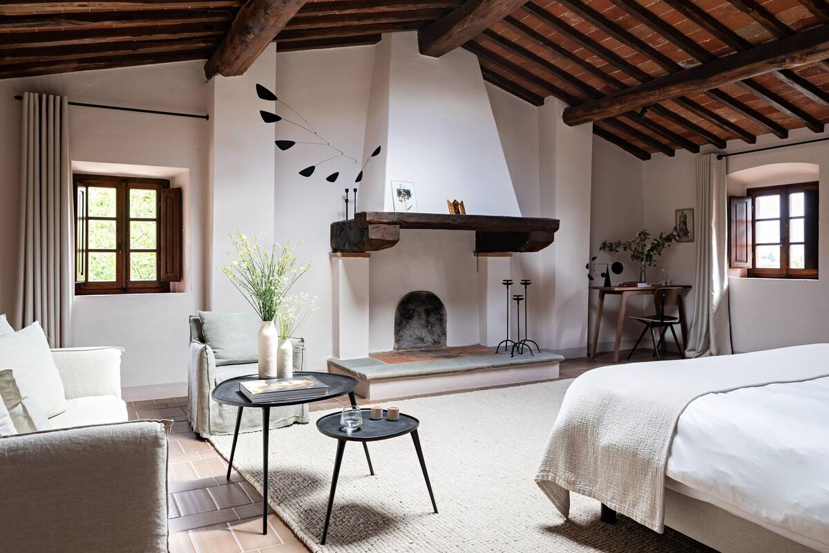 A cozy room with a fireplace, a sofa, a bed, and a small table with a vase and candles.