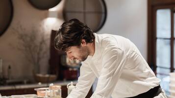 A person working at a marble counter in a kitchen with round wall decorations and a window.