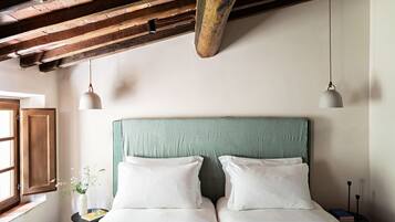 Una stanza con un letto, un comodino, una finestra e una lampada a sospensione.