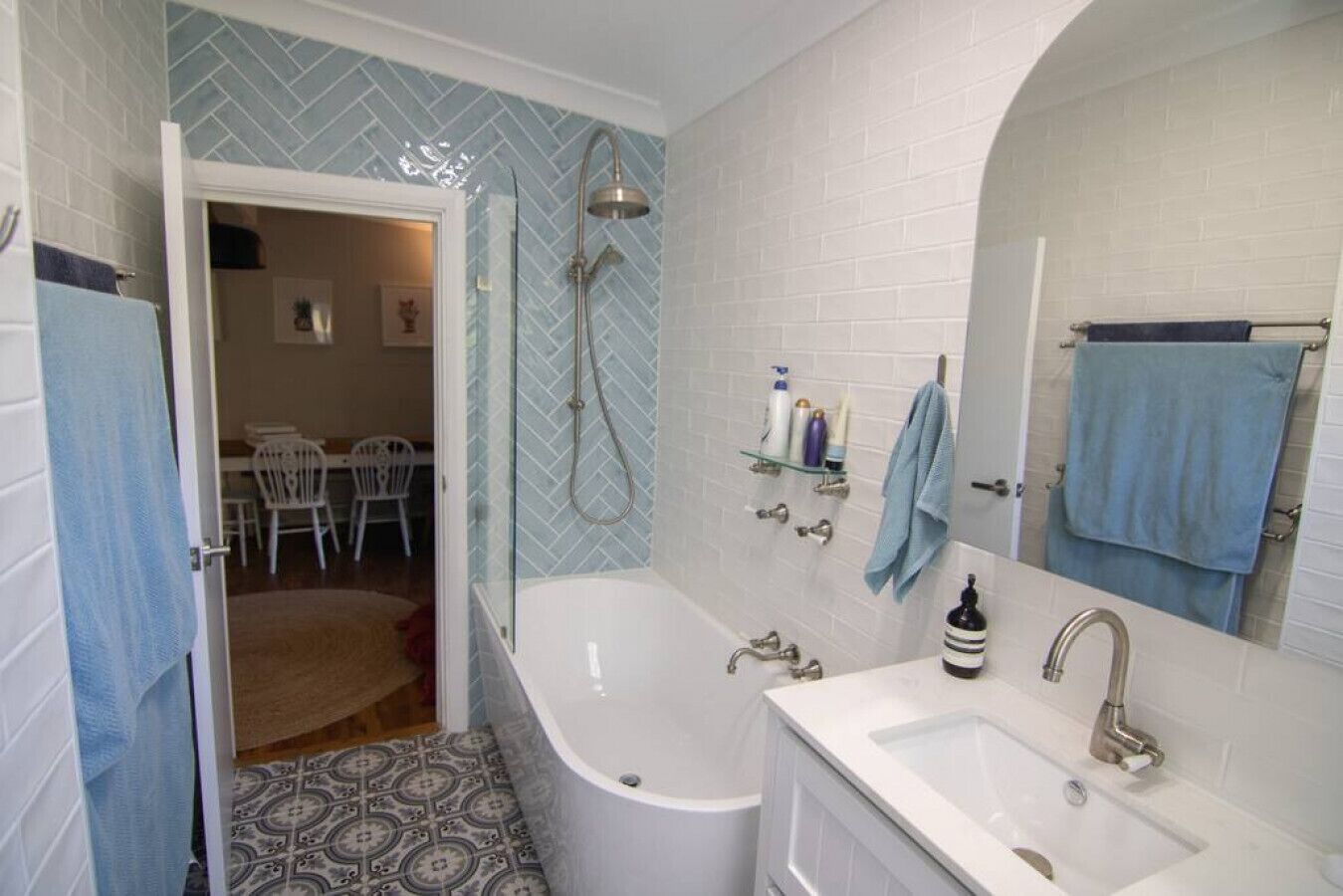 Un baño con bañera, ducha, lavamanos y espejo. Hay toallas colgadas en la pared y una cortina de ducha.