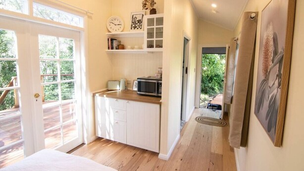 A kitchen with white cabinets, a microwave, and a clock on the wall.