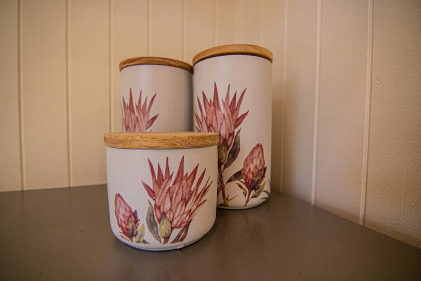 Two cylindrical containers with floral designs and wooden lids.