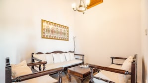 Een kamer met een houten bed, een houten bank, een houten salontafel en een kroonluchter.