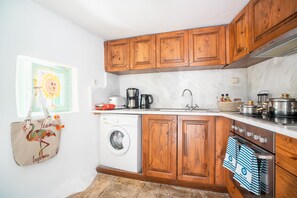 A kitchen with wooden cabinets, a washing machine, a stove, and a sink.